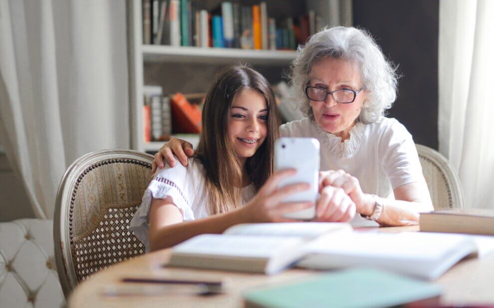 Mädchen und ältere Frau schauen gemeinsam auf ein Smartphone